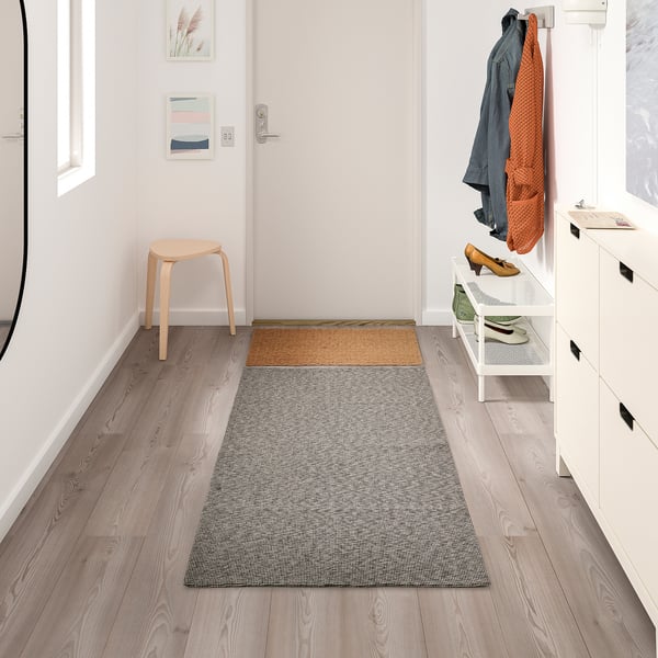 Modern entryway with TIPHEDE grey cotton rug, between stool and shoe rack.