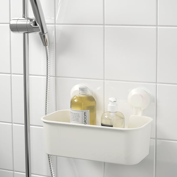 White wall-mounted bathroom caddy holds shampoo and soap bottles, using suction cups on tiled wall near showerhead.
