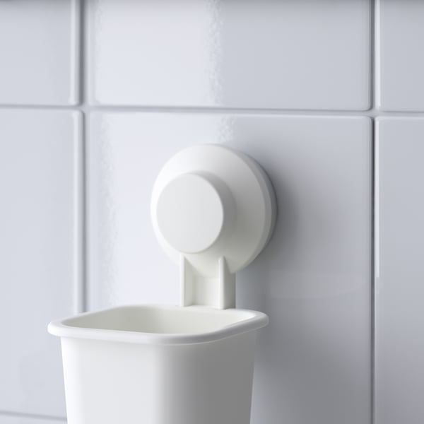 Wall-mounted holder with suction cup, securely holding a small white container.