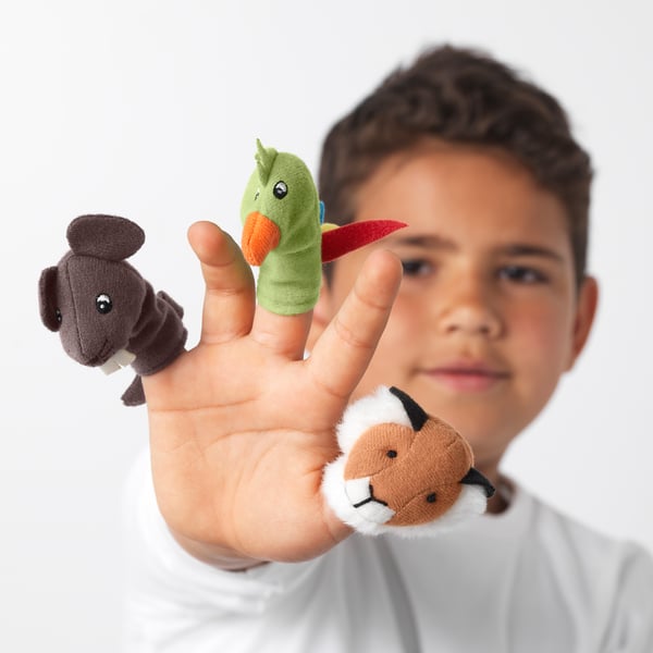 Boy holding three finger puppets: a bear, a duck, and a cat.