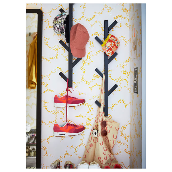 Modern wall-mounted coat rack with black branches, orange accessories.