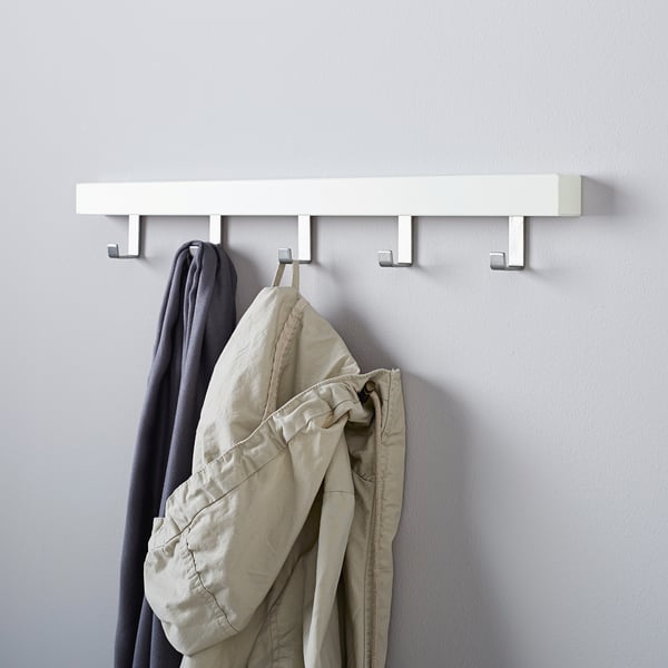 Wall-mounted coat rack TJUSIG with 4 hooks, holding jackets and a scarf, organising entryway or hallway.