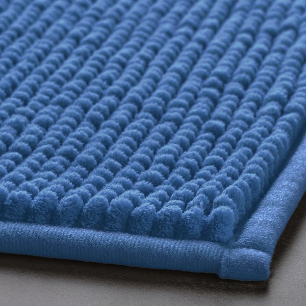 Blue textured bath mat with soft, cloud-like surface pattern, folded slightly to show depth and quality.