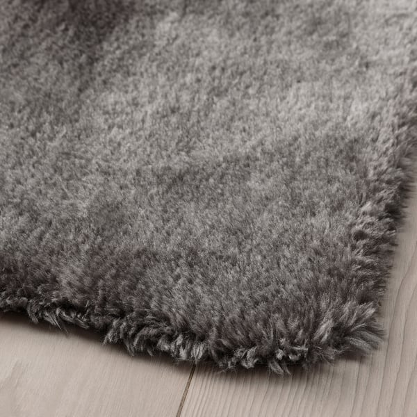 Close-up of soft, plush grey rug with textured, shaggy surface on hardwood floor.