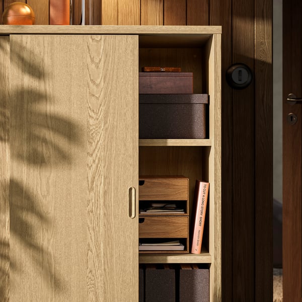 Wooden cabinet with sliding door, revealing shelves for organised storage.