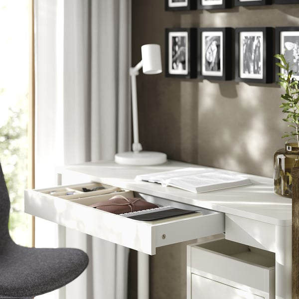 White TONSTAD desk, narrow & sleek, organised with open drawer, books, lamp and plant.