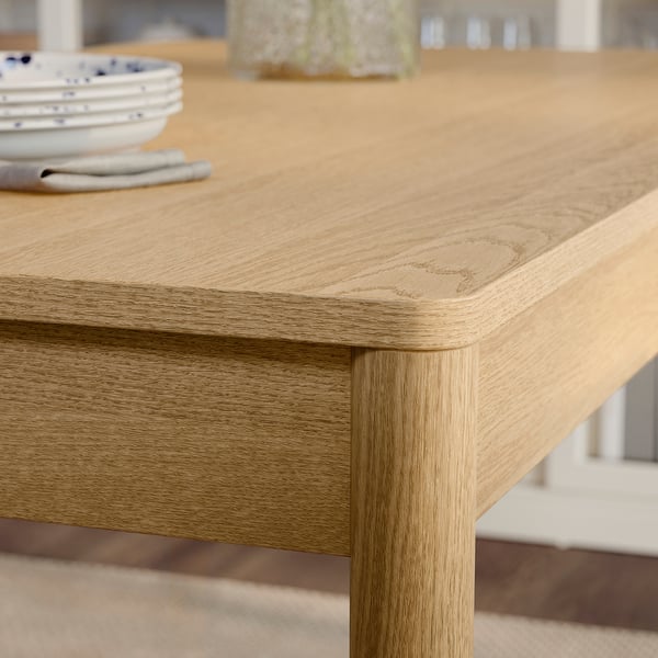Wooden table close-up, smooth surface, rounded edges, light wood grain visible, showing craftsmanship and quality.