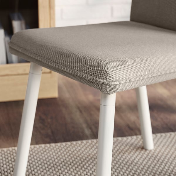 A modern dining chair with a cushion seat, four slender white legs, and a textured fabric cover in a neutral tone.