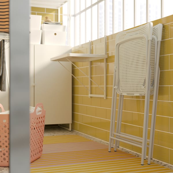 A white plastic TORPARÖ chair in a room with a colourful rug.