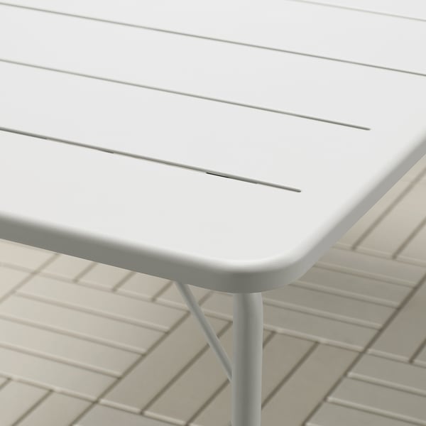 Close-up of modern white tables surface and sleek metal leg, showcasing its clean design and durable materials.