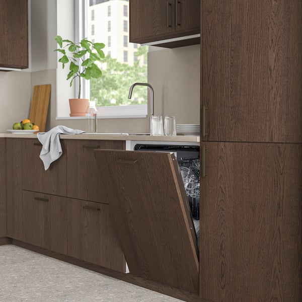 Modern kitchen with dark cabinets, partially open dishwasher near sink, natural light from window.