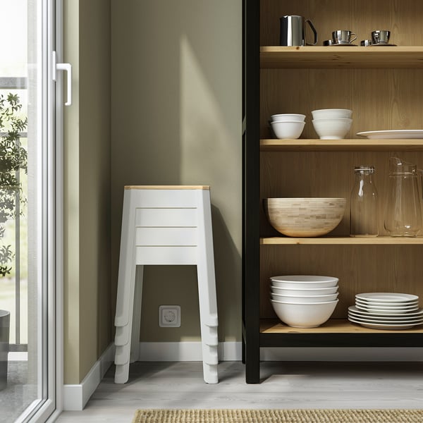 Modern kitchen corner with open shelf, TRÄNNÖ stool, green wall.
