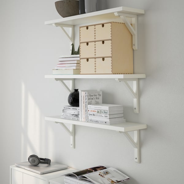 A wall-mounted white shelf with wooden storage boxes, books, and a black decorative vase, displaying and organizing items neatly.