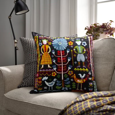 Black TRATTKAKTUS sofa cushion with colourful folk designs.