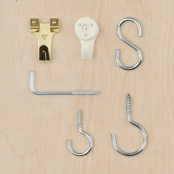 TRIXIG hardware set: gold and silver hooks, nails, and plastic box on wood.