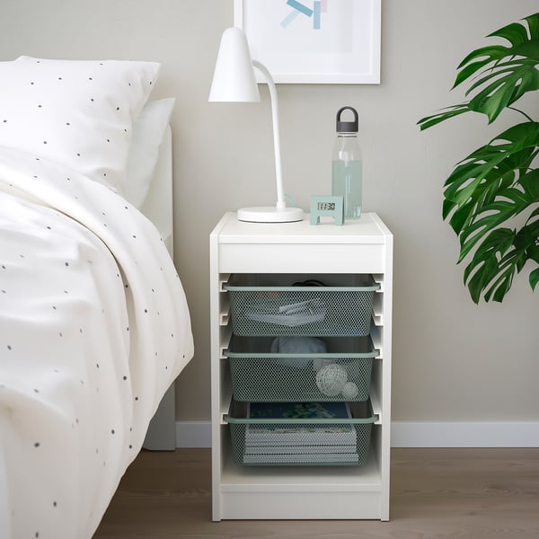 TROFAST: white bedside storage with mesh drawers. Plant, lamp, and water bottle nearby.