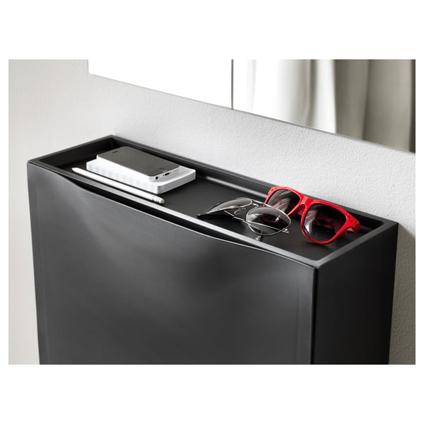 Black TRONES shoe cabinet with shallow top for keys and phone, placed against white wall.