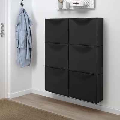 Black TRONES cabinet offers shallow storage, ideal for small spaces. Holds wall hook with blue jacket.