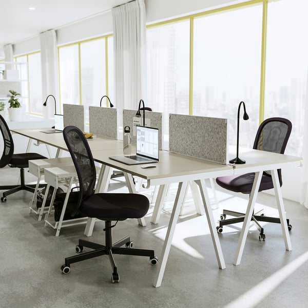 Modern office with TROTTEN desks, black chairs, lamps, acoustic panels, and large windows.
