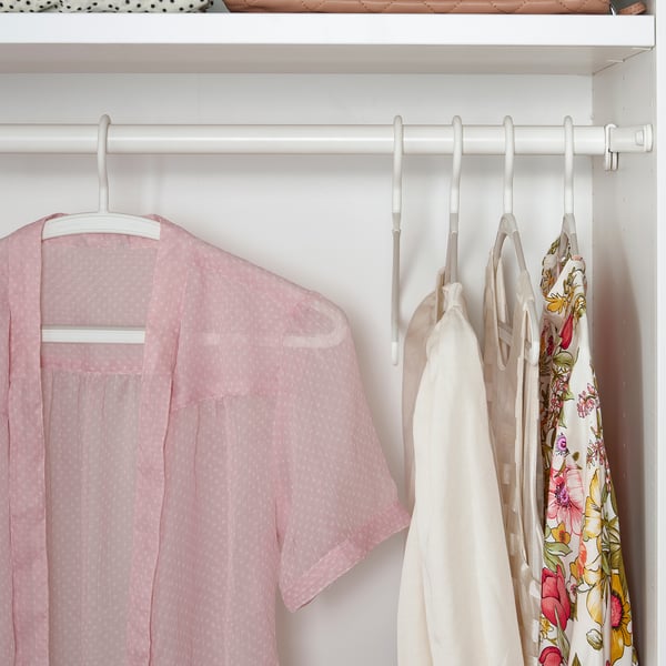 Closet with light pink garments on white anti-slip hangers.