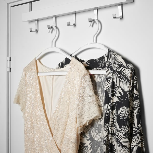 Two dresses hang on an anti-slip hanger, one beige lace, the other black and white floral.