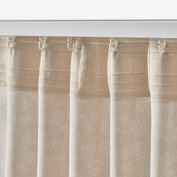 Beige and white patterned curtains hang, filtering light and offering privacy. Hook attachments visible at the top.