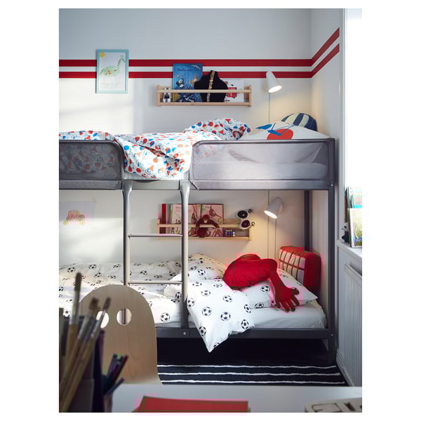 Kids bunk beds with soccer bedding, bookshelf, night light, desk, drawing supplies, colorful pillows.