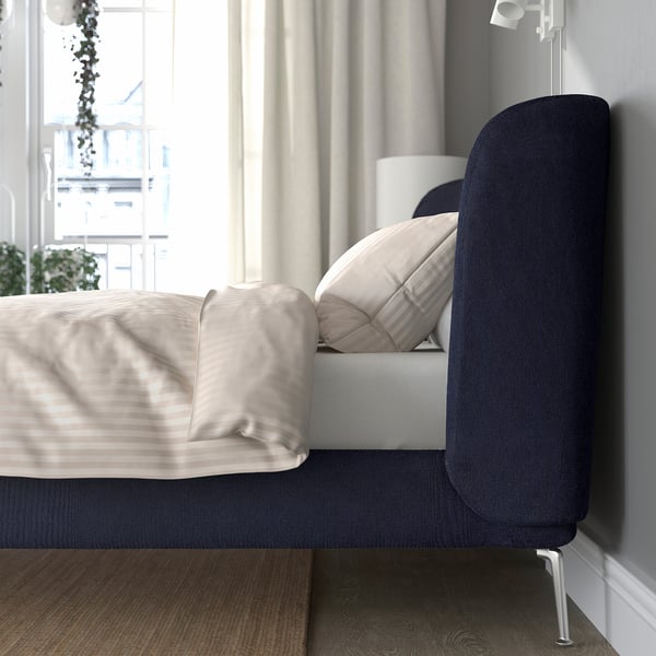 A modern bed with a curved headboard, soft upholstery, and adjustable sides for various mattress thicknesses.