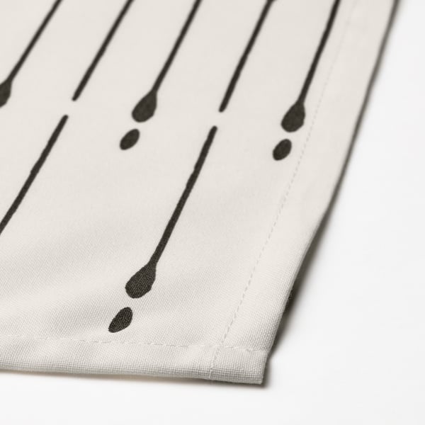 Close-up of recycled polyester tablecloth, black lines on white, showing stitching and fabric texture.