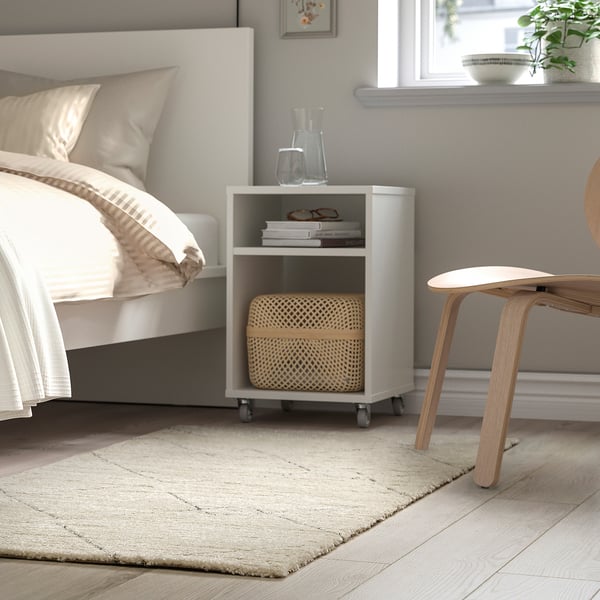 Minimalist bedroom with white bed, nightstand, large berber-inspired rug beside bed.