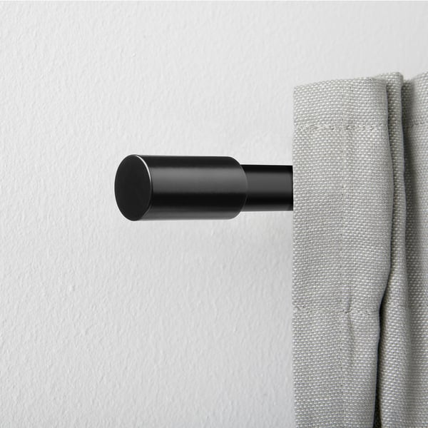 Black aluminium cylinder finial on curtain rod, modern design. Small, sleek, and minimalistic.