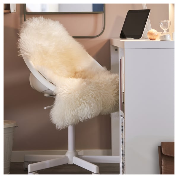Sheepskin rug on office chair with laptop nearby.