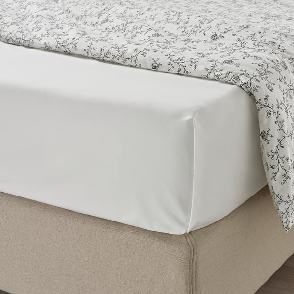 Neat bed with white ULLVIDE sheets, subtle floral pattern, soft & absorbent.