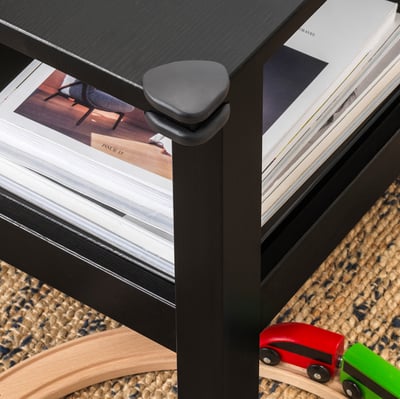 Dark brown corner bumpers on table edges safeguard kids from sharp corners. Books and toys are nearby, emphasising child-friendly design.