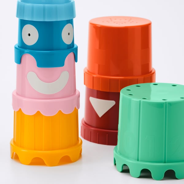 Four colourful plastic stacking cups with playful faces, brightly coloured and arranged on a white surface.