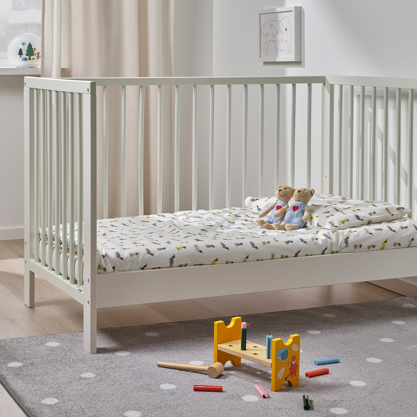Playful kids bed with prints and teddies, on a grey rug, near a toy hammer set.