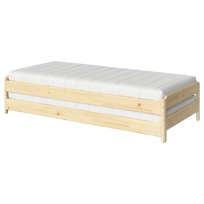 An ikea UTÅKER wooden bed with a white mattress, designed for space-saving and easy conversion.