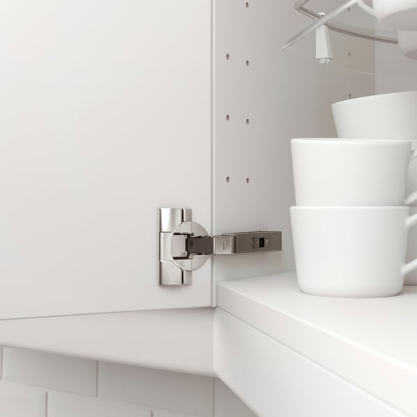 A close-up of a kitchen cabinet hinge attaches a door; it is adjustable and used for a corner unit.