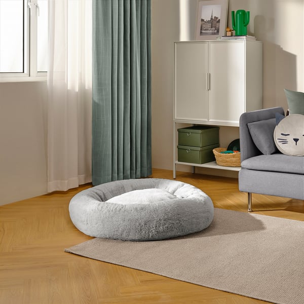 A cosy, round dog bed sits on a rug in a living room, providing a soft spot for pets to relax.