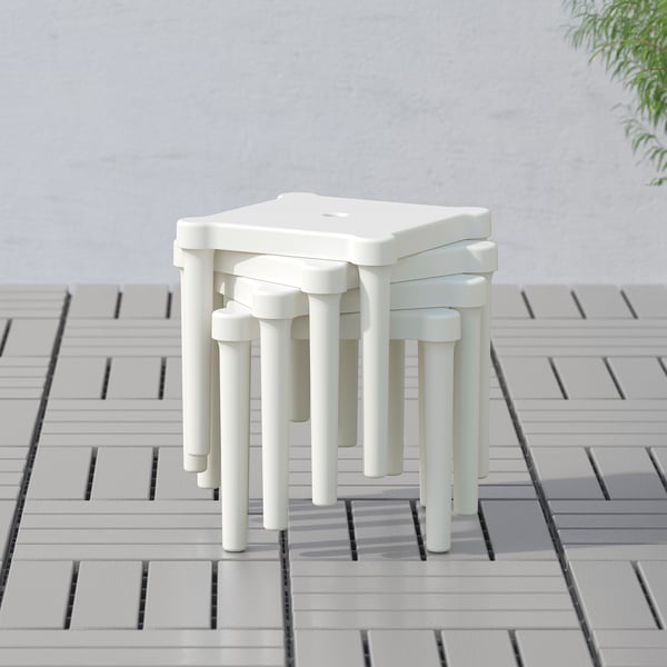 Stackable white childrens stools outdoors on tiled patio, ideal for play and crafts.