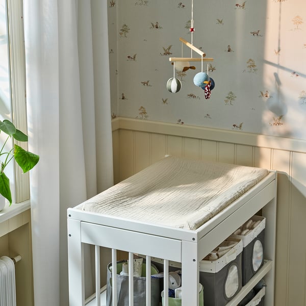 IKEA VÄDRA changing table with cat cover, wall, shelves, plant.