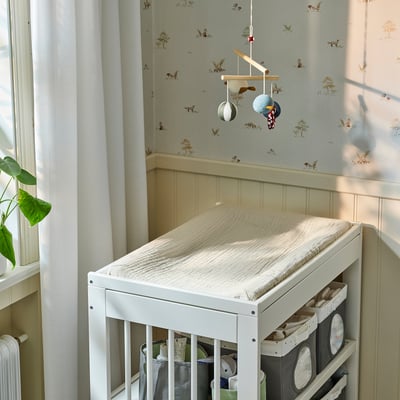 IKEA VÄDRA changing table with cat cover, wall, shelves, plant.