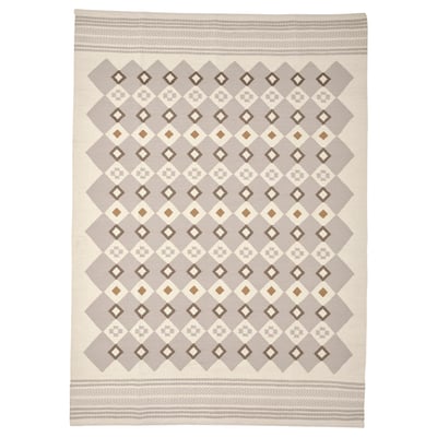 A neutral-toned, handwoven wool rug named VÄGNÄT with intricate geometric patterns and decorative borders.