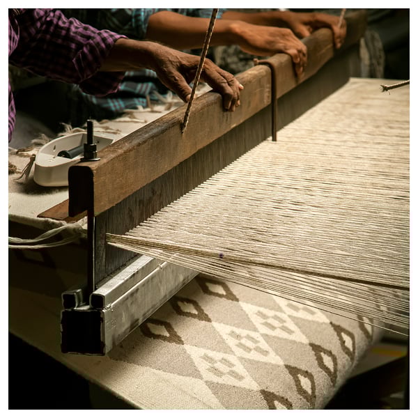 Image hands weaving VÄGNÄT rug. Cream and grey with traditional pattern. Crafted with cotton and wool for durability.