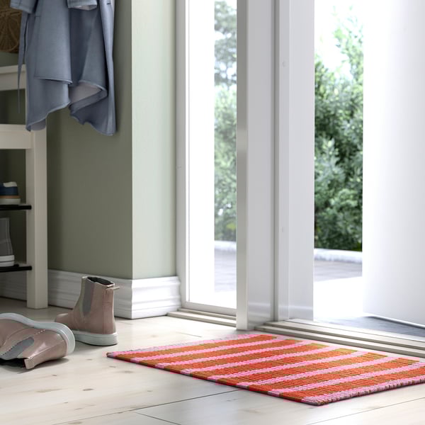 Bright orange and white striped VÄGSKYLT mat, small, fits near door, made of cotton, machine washable, backed with glue.