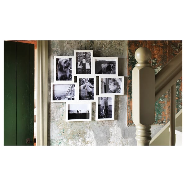 White VÄXBO photo frame collage with black & white images. Displays eight photos in a grid layout. Set against a distressed wall and green door.