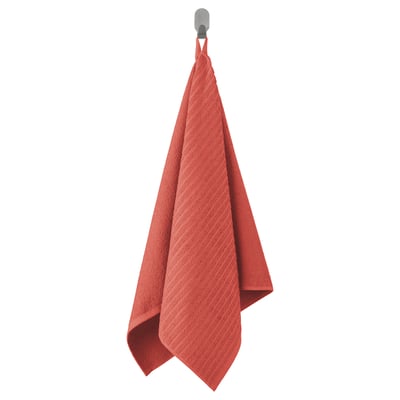 A red VÅGSJÖN towel hangs on a hook, soft cotton material, rectangular shape with textured weave.
