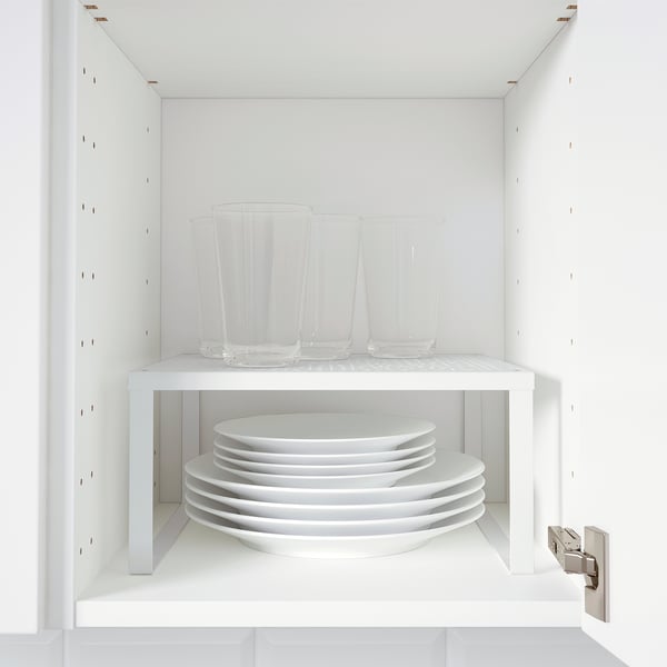 White cabinet with VARIERA shelf insert: clear glasses on top, stacked white plates below.