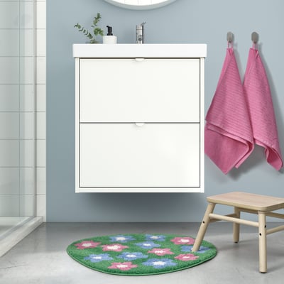 Bathroom with white cabinet, sink, mirror. VATTENSKRUV green bath mat with flowers, stool, pink towels.