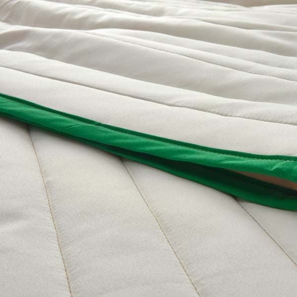 Elegant, recycled fabric bedspread in white with dark green trim showcasing premium texture and design.